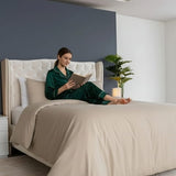Muestra a una chica leyendo un libro sentada sobre una cama, tendida con nuestro heromoso Combo Sahara Amare.
