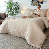 Dama sentada en una cama tendida con el Duvet Cover Dolcce Caramelo mientras lee un libro.